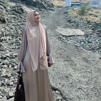Titi Kamal memakai hijab pashmina warna nude yang dipadu dengan dres shimmer silk warna senada saat berpose di kawasan Jabal Tsur, Mekkah.  Foto: Dok. Instagram @titi_kamall.