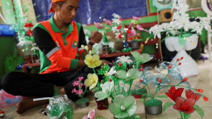 Plastic recycled flowers are displayed while a municipality worker makes a handicraft at the Setu reservoir area in Jakarta, Indonesia, January 29, 2024. REUTERS/Ajeng Dinar Ulfiana