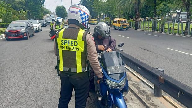 Polisi menilang pemotor bandel yang mellintasi Jembatan Mayangkara