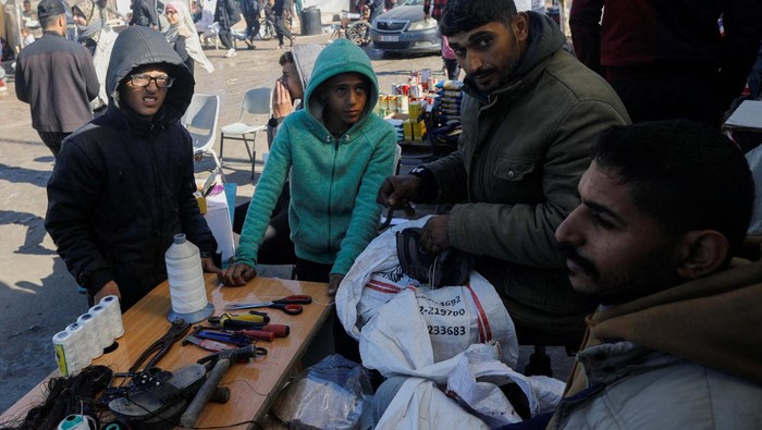 Displaced Palestinians, who fled their houses due to Israeli strikes, wait to get their slippers repaired by a cobbler, amid shortages of new footwear, in Rafah in the southern Gaza Strip January 31, 2024. REUTERS/Saleh Salem