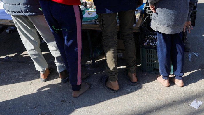 Displaced Palestinians, who fled their houses due to Israeli strikes, wait to get their slippers repaired by a cobbler, amid shortages of new footwear, in Rafah in the southern Gaza Strip January 31, 2024. REUTERS/Saleh Salem