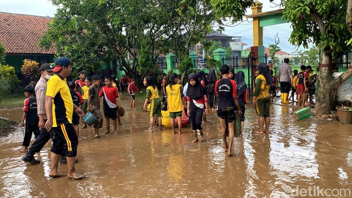 Siswa SDN Gamblang bersihkan lumpur sisa banjir di sekolahnya.
