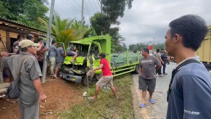 Warga membantu mengevakuasi korban yang terjepit bodi depan truk di jalinsum Lubuklinggau.