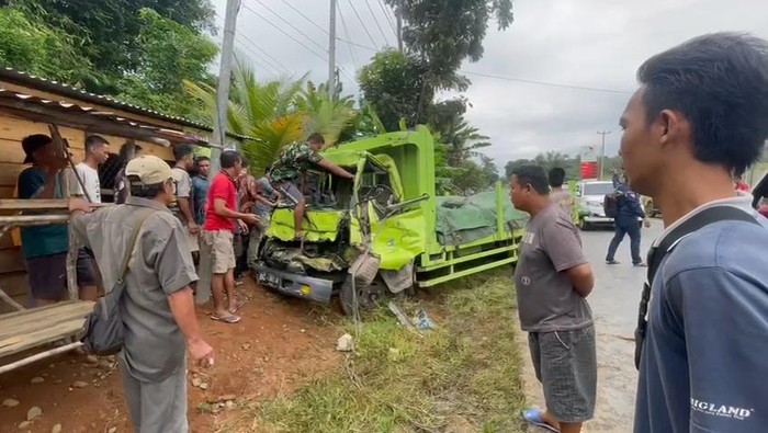 Warga membantu mengevakuasi korban yang terjepit bodi depan truk.