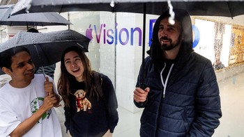 Walaupun hujan mereka tetap antusias menunggu gilirannya untuk mencoba headset Vision Pro. Foto: AP/Noah Berger