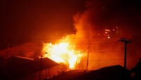 Tampak api membesar membakar sebuah rumah.