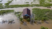 Foto udara seorang warga berjalan menerobos banjir.
