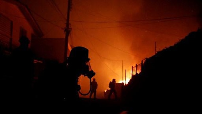 Firefighters try to put out a fire in Via del Mar, Chile, on February 2, 2024. A huge mushroom cloud of smoke hangs over tourist areas in central Chile, including Via del Mar and Valparaiso, where a forest fire broke out on Friday, threatening hundreds of homes and forcing the evacuation of residents. (Photo by Javier TORRES / AFP)