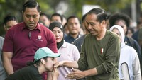 Seorang warga mencium tangan Jokowi yang sedang melakukan jalan santai bareng keluarga. 