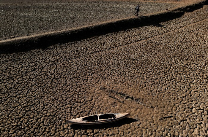 Residents walk on cracked ground next to the village of San Roman de Sau, at Sau reservoir which was partially submerged, though it later re-emerged, as the Iberian peninsula is at its driest in 1,200 years Spain, January 31, 2024. REUTERS/Nacho Doce