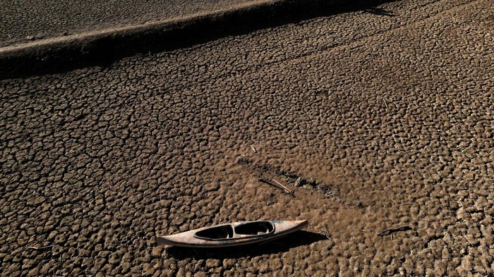 Residents walk on cracked ground next to the village of San Roman de Sau, at Sau reservoir which was partially submerged, though it later re-emerged, as the Iberian peninsula is at its driest in 1,200 years Spain, January 31, 2024. REUTERS/Nacho Doce