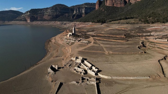 Air Waduk Menyusut Parah, Catalonia Spanyol Umumkan Darurat Kekeringan Residents walk on cracked ground next to the village of San Roman de Sau, at Sau reservoir which was partially submerged, though it later re-emerged, as the Iberian peninsula is at its driest in 1,200 years Spain, January 31, 2024. REUTERS/Nacho Doce
