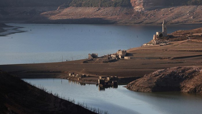 Residents walk on cracked ground next to the village of San Roman de Sau, at Sau reservoir which was partially submerged, though it later re-emerged, as the Iberian peninsula is at its driest in 1,200 years Spain, January 31, 2024. REUTERS/Nacho Doce