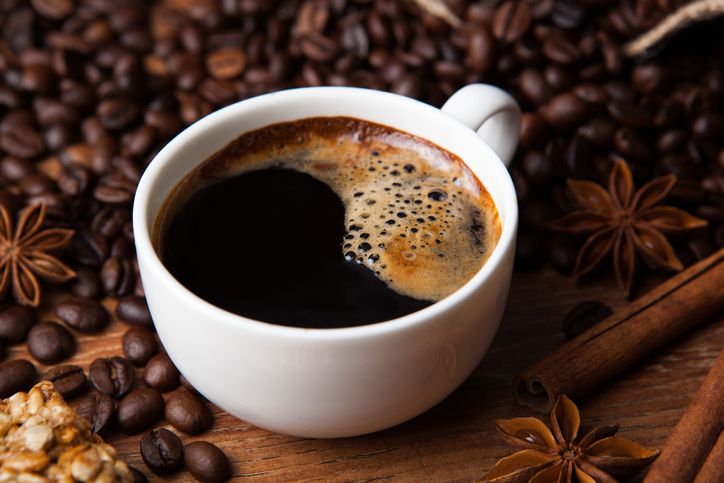 cup of black coffee and cinnamon sticks closeup