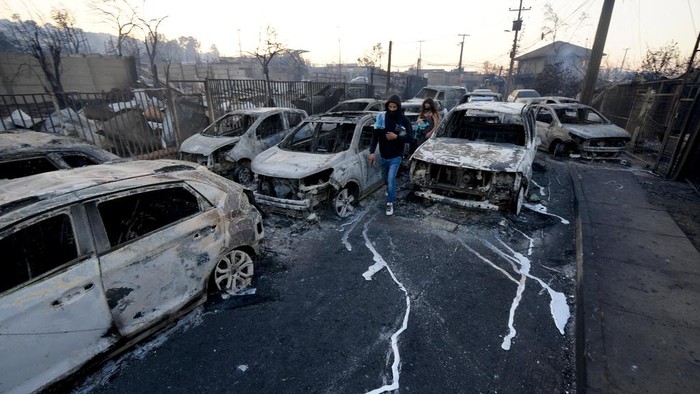 A person looks at a burned-out house after a forest fire reached Villa Independencia neighborhood in Vina del Mar, Chile, Saturday, Feb. 3, 2024. (AP Photo/ Esteban Felix)