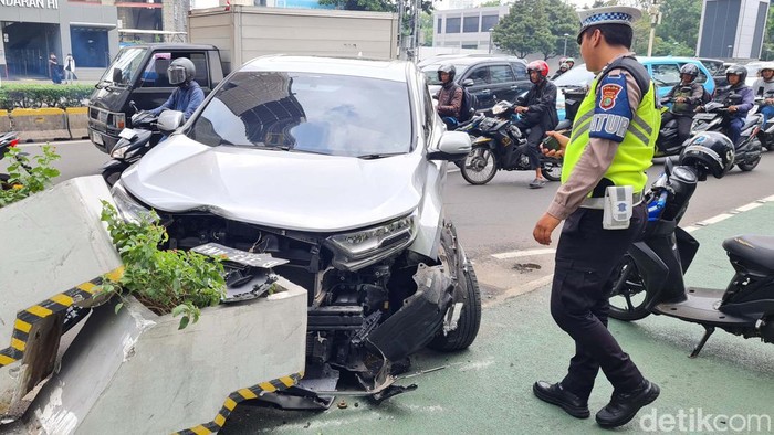 Sebuah mobil Honda CRV  menabrak beton pembatas jalur sepeda di Jalan MH Thamrin, Jakarta, Selasa (6/2/2024). Bagian depan mobil ringsek.