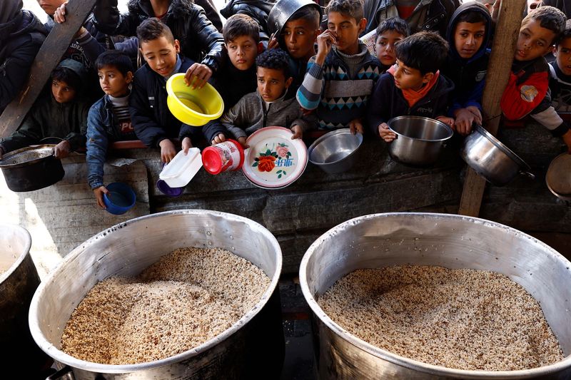 Palestinians wait to receive food cooked by a charity kitchen amid shortages of food supplies, amid the ongoing conflict between Israel and the Palestinian Islamist group Hamas, in Rafah in the southern Gaza Strip, January 16, 2024. REUTERS/Saleh Salem     TPX IMAGES OF THE DAY
