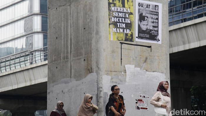 Warga melintas di depan fotokopi kliping koran tahun 98 terkait kasus pelanggaran HAM yang dipasang di halte dan jalur pedestrian, Jl Rasuna Said, Jakarta, Selasa (6/2/2024).
