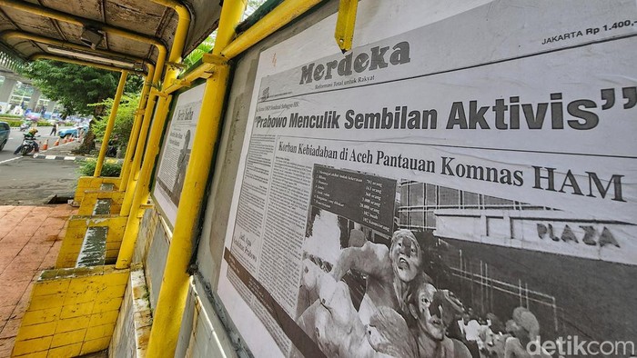 Warga melintas di depan fotokopi kliping koran tahun 98 terkait kasus pelanggaran HAM yang dipasang di halte dan jalur pedestrian, Jl Rasuna Said, Jakarta, Selasa (6/2/2024).