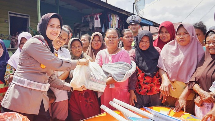 Kasat Lantas Polres Rohil Iptu  Zahratul Aulia Harun saat mendistribusikan bantuan untuk masyarakat korban banjir. (Dok Polres Rohil)