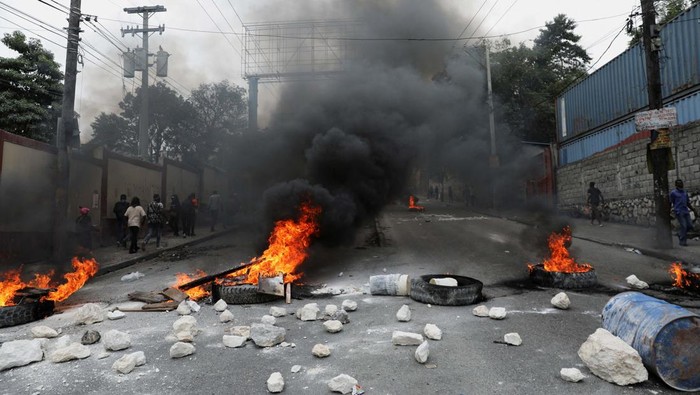 People react as they walk near a burning barricade set up in protest against the government and calling for the resignation of Prime Minister Ariel Henry, in Port-au-Prince, Haiti February 5, 2024. REUTERS/Ralph Tedy Erol