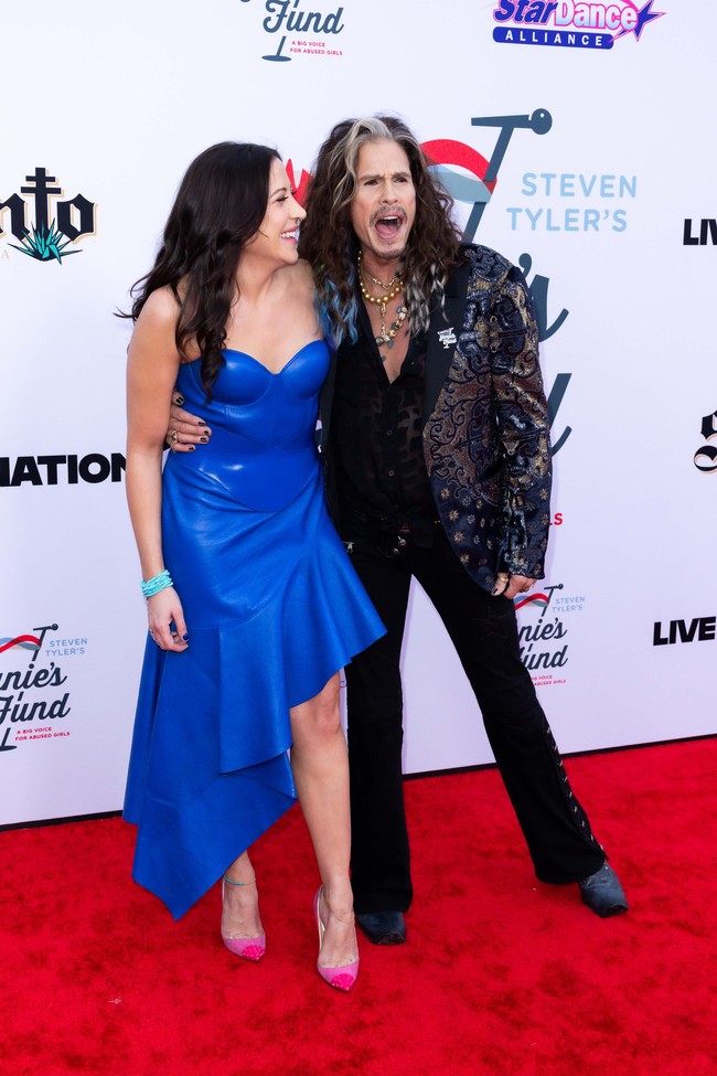 Ayah aktris Liv Tyler ini mengenakan celana jeans hitam model boot cut dan kemeja serta blazer bersulam hitam-emas. Dia melengkapi penampilannya dengan ikat pinggang berhias stud dan bertabur, dan beberapa kalung warna-warni. Foto: Getty Images/Elyse Jankowski