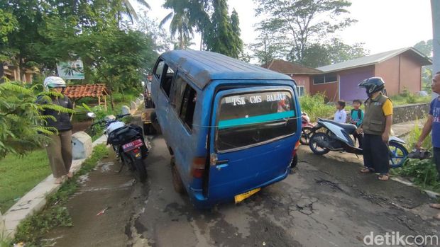 Warga bergotong royong mengangkat mobil angkutan umum yang terguling ke sawah di Pawindan Ciamis.