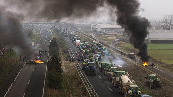 Aksi Protes Petani Spanyol, Blokir Jalan dengan Traktor hingga Bakar Ban Farmers make barricades after blocking a highway during a protest near Mollerussa, northeast Spain, Tuesday, Feb. 6, 2024. From early morning, farmers across Spain have staged tractor protests across the country, blocking highways and causing traffic jams to demand changes in European Union policies and funds and measures to combat production cost hikes. (AP Photo/Emilio Morenatti)