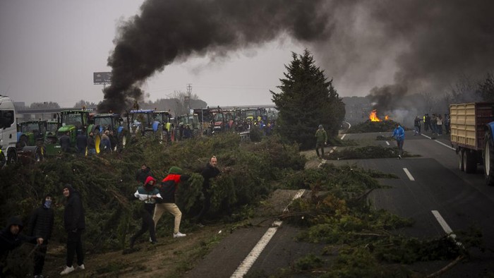 Aksi Protes Petani Spanyol, Blokir Jalan dengan Traktor hingga Bakar Ban Farmers make barricades after blocking a highway during a protest near Mollerussa, northeast Spain, Tuesday, Feb. 6, 2024. From early morning, farmers across Spain have staged tractor protests across the country, blocking highways and causing traffic jams to demand changes in European Union policies and funds and measures to combat production cost hikes. (AP Photo/Emilio Morenatti)