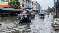 Seorang pengendara motor terjebak banjir di Jalan Pepelegi, Waru. Sidoarjo.