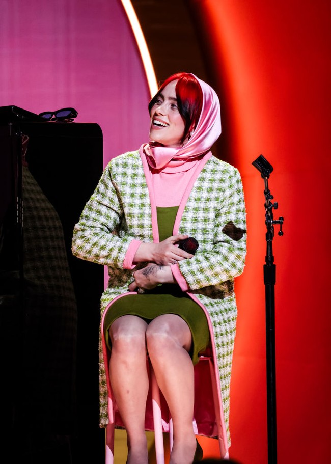 Billie Eilish mengenakan gaun turtle neck berbahan rajut yang dipadu cardigan panjang motif gingham berwarna hijau-pink. Foto: FilmMagic/Timothy Norris