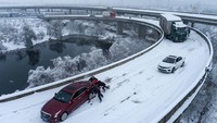 Orang-orang mendorong mobil yang terjebak di jalan raya setelah hujan salju lebat di wilayah tersebut, di Wuhan, Provinsi Hubei, China, 6 Februari 2024. China Daily via REUTERS.