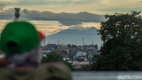 Salah satunya dari Jembatan Ciliwung Kalibata, Jakarta Timur. Warga yang tengah melintas pun berhenti sejenak untuk menyaksikan keindahan gunung.