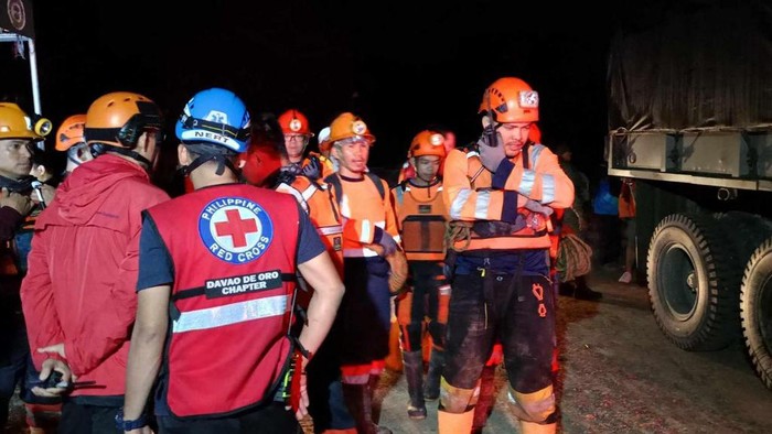 This handout photo taken on February 6, 2024 and released on February 7 by the Philippine Red Cross - Davao de Oro Chapter shows personnel arriving for search and rescue operations following a landslide in Maco municipality in Davao de Oro province. At least 11 people were injured when a rain-induced landslide buried two buses picking up workers from a gold mine in the southern Philippines, officials said. (Photo by Handout / Philippine Red Cross - Davao de Oro Chapter / AFP) / RESTRICTED TO EDITORIAL USE - MANDATORY CREDIT AFP PHOTO / Philippine Red Cross - Davao de Oro Chapter - NO MARKETING NO ADVERTISING CAMPAIGNS - DISTRIBUTED AS A SERVICE TO CLIENTS