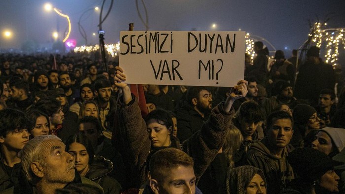 Warga Turki Peringati Satu Tahun Gempa yang Tewaskan 60 Ribu Orang People gather to mark the one-year anniversary of the country's catastrophic earthquake, in the city of Antakya, southern Turkey, Tuesday, Feb. 6, 2024. A banner reads
