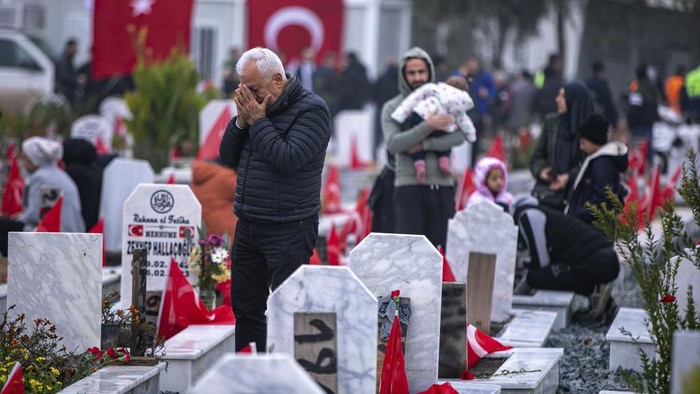 People gather to mark the one-year anniversary of the country's catastrophic earthquake, in the city of Antakya, southern Turkey, Tuesday, Feb. 6, 2024. A banner reads 