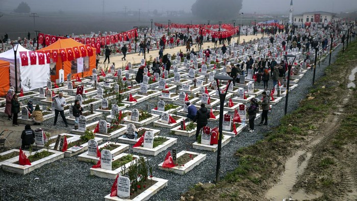 People gather to mark the one-year anniversary of the country's catastrophic earthquake, in the city of Antakya, southern Turkey, Tuesday, Feb. 6, 2024. A banner reads 