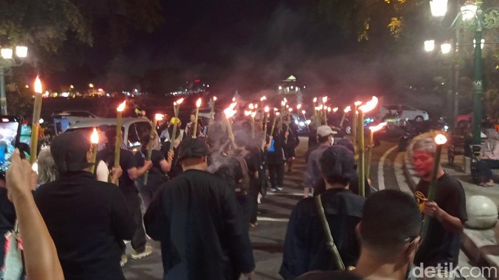 Para eks Aktivis 98 menggelar aksi jalan mundur sambil membawa obor dari sekitar Alun-Alun Utara menuju Gedung Agung Istana Presiden pada Kamis malam (8/2/2024).