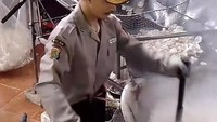 Kostum atau seragam petugas keamanan atau satpam ini, Jeni pakai saat menggoreng kerupuk dengan ekspresi serius. Foto: TikTok @_gemini115
