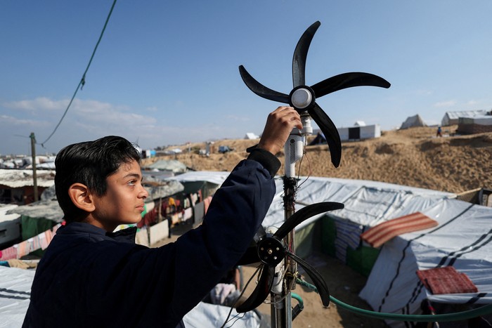 Displaced Palestinian teenager Hussam Al-Attar, nicknamed by people Newton, works on wind turbines, that he uses to light up his shelter during power cut, at a tent camp in Rafah, in the southern Gaza Strip, February 6, 2024. REUTERS/Ibraheem Abu Mustafa     TPX IMAGES OF THE DAY