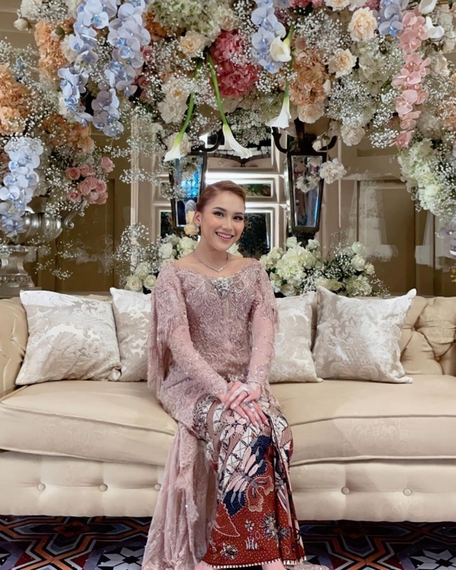 Ayu Ting Ting tampil dengan kebaya vibes lamaran di foto ini. Pemain Lapor Pak! itu berkebaya warna pink pastel saat menghadiri resepsi pernikahan adiknya, Syifa, pada 2022 lalu. Penampilannya bak wanita lamaran ditambah dengan gaya rambutnya yang disanggul cepol ditambah aksesori bunga. Foto: Dok. Instagram