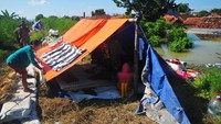 Warga ngungsi di tenda darurat yang didirikan di tanggul sungai.  