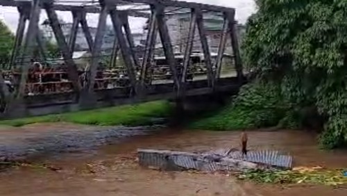 Pemilik rumah berdiri diatas atap rumah nya yang sedang terseret banjir di Kampung Bugis Sumbawa.
