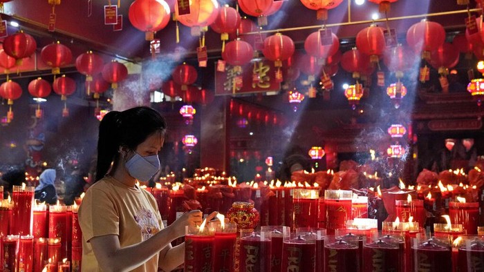 A woman lights a candle during the lunar New Year celebrations at the Hok Lay Kiong temple in Bekasi, Indonesia, Tuesday, Feb. 1, 2022. The celebration marks the Year of the Tiger in the Chinese Zodiac calendar. (AP Photo/Dita Alangkara)