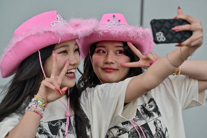 Fans of US singer Taylor Swift, also known as Swifties, pose for photos outside the Tokyo Dome shortly before the start of the first leg of her Asia-Pacific 