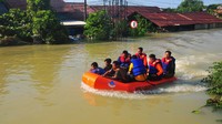 Tim SAR dengan perahu karet melintasi banjir yang tingginya nyaris mencapai atap rumah warga.