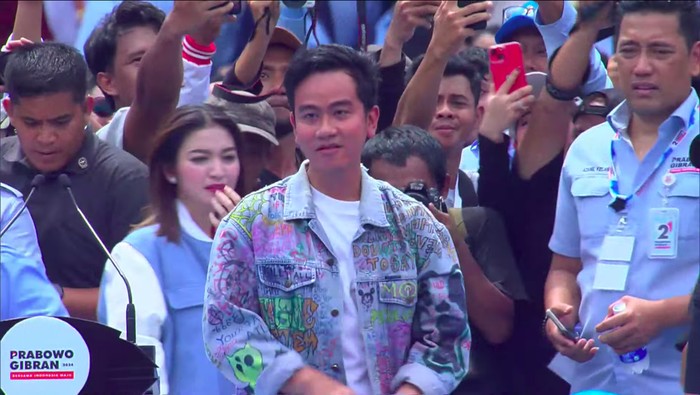Cawapres Gibran Rakabuming memasuki area kampanye akbar di Stadion GBK dengan berkonvoi sepeda motor. Gibran tampak membonceng sang istri, Selvi Ananda. (YouTube Waktunya Indonesia Maju)