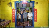 Potret keluarga bapak Heri di depan pintu masuk rumahnya yang penuh dengan simbol umat Tionghoa.