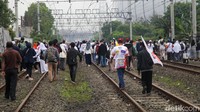 Massa pendukung AMIN menyusuri rel kereta dengan membawa sejumlah bendera dan spanduk.