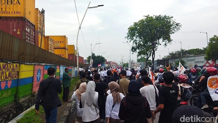 Pendukung Anies Baswedan-Muhaimin Iskandar (Cak Imin) long march menuju lokasi Kumpul Akbar di Jakarta Internasional Stadium (JIS) karena lalu lintas macet. (Kurniawan F/detikcom)